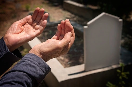Man praying on a grave stone
